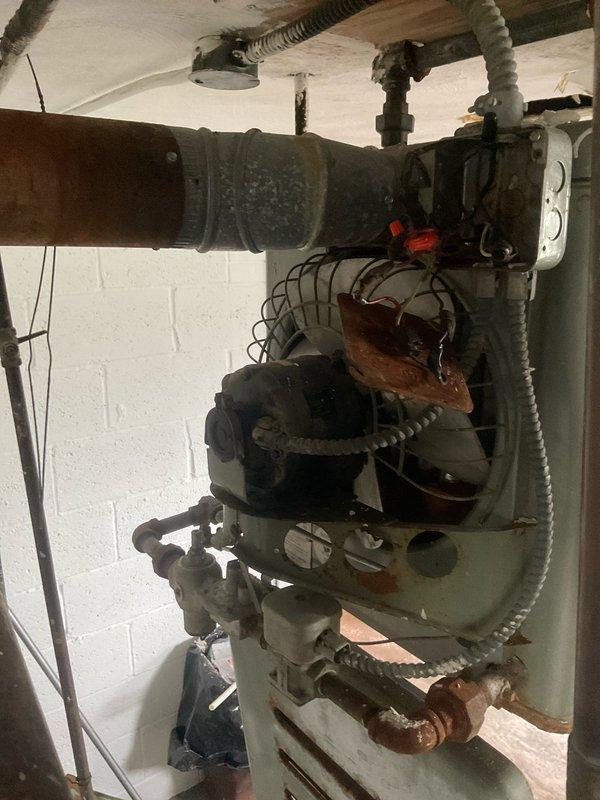 Conducted inspection of aging tanked water heater system with significant corrosion and deterioration evident throughout the installation. Assessment revealed a Reznor unit with extensive rust damage to the lower section, compromised copper components, and potential ventilation issues. Recommended replacement of the 30-gallon water heater due to end-of-life condition and safety concerns.