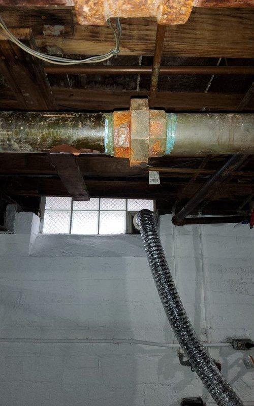 Addressed severe corrosion and leakage at hydronic radiator pipe union in basement. Replaced deteriorated pipe section and fitting that showed significant rust formation and water damage to surrounding joists. Pressure tested system after repair to verify integrity of copper distribution lines and ensure proper operation of heating system.