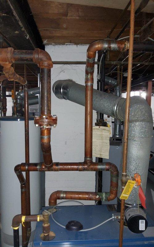 Addressed severe corrosion and leakage at hydronic radiator pipe union in basement. Replaced deteriorated pipe section and fitting that showed significant rust formation and water damage to surrounding joists. Pressure tested system after repair to verify integrity of copper distribution lines and ensure proper operation of heating system.