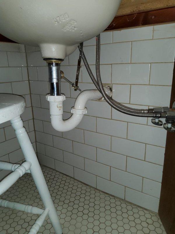 Performed faucet replacement in a century-old home with deteriorating plumbing infrastructure. Installed new P-trap assembly with PVC piping and braided supply lines beneath bathroom sink. Identified and documented water damage and corrosion at pipe junctions in basement, particularly where dissimilar metals connect, which may require future attention.