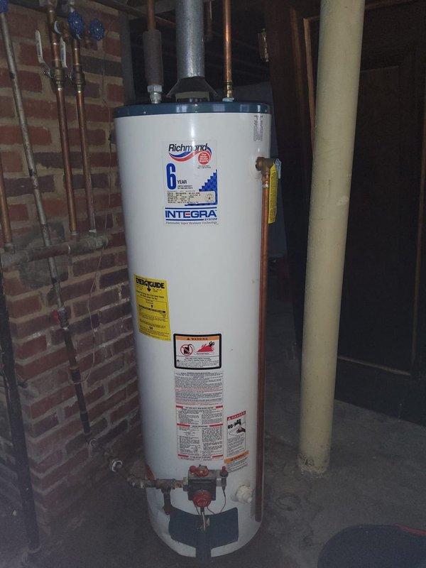 Performed second opinion evaluation on 30+ year old boiler system after previous repair resulted in leakage. Inspection revealed aging installation with standard expansion tank mounted on brick chimney structure and copper distribution piping. Richmond "INTEGRA" water heater with 8-year warranty also present in utility area, appearing in functional condition with no visible issues. Recommended comprehensive assessment of pressure relief valve and system components to address ongoing leakage concerns.