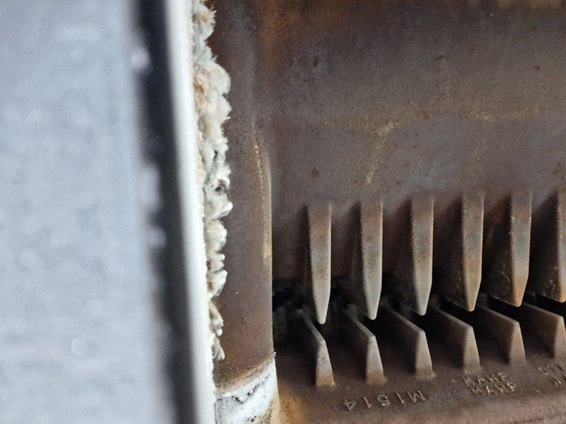Performed scheduled Heating Tune Up under Home Plan on boiler system. Identified significant corrosion and rust on heat exchanger fins with substantial dust/debris accumulation between fins. Observed deterioration of metal components and compromised insulation/sealant at connection points requiring attention for optimal system performance.
