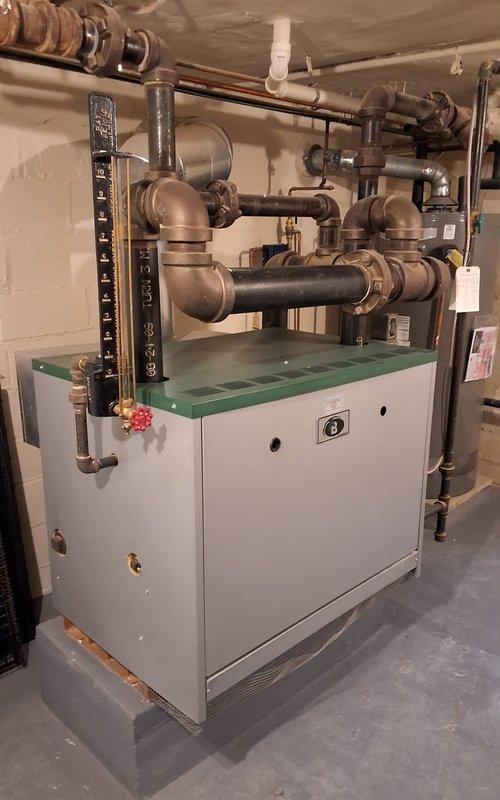 Completed scheduled follow-up service on steam radiator system after customer's ceiling was opened to provide access. Inspected aging boiler system (9 years old) and associated copper piping network. Noted digital monitoring device (VXT) displaying reading of 301, verified proper operation of valves and pressure gauges, and ensured all connections were secure throughout the extensive piping infrastructure.