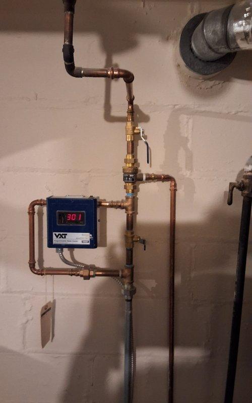 Completed scheduled follow-up service on steam radiator system after customer's ceiling was opened to provide access. Inspected aging boiler system (9 years old) and associated copper piping network. Noted digital monitoring device (VXT) displaying reading of 301, verified proper operation of valves and pressure gauges, and ensured all connections were secure throughout the extensive piping infrastructure.