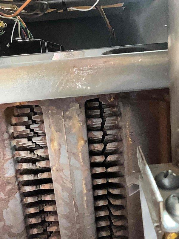 Performed scheduled heating tune-up on 4-year-old MVP system, which had been rescheduled twice. Inspected heat exchanger showing signs of corrosion and moisture accumulation in collection pan. Verified proper burner operation with strong blue flames at base transitioning to orange tips, indicating normal combustion.