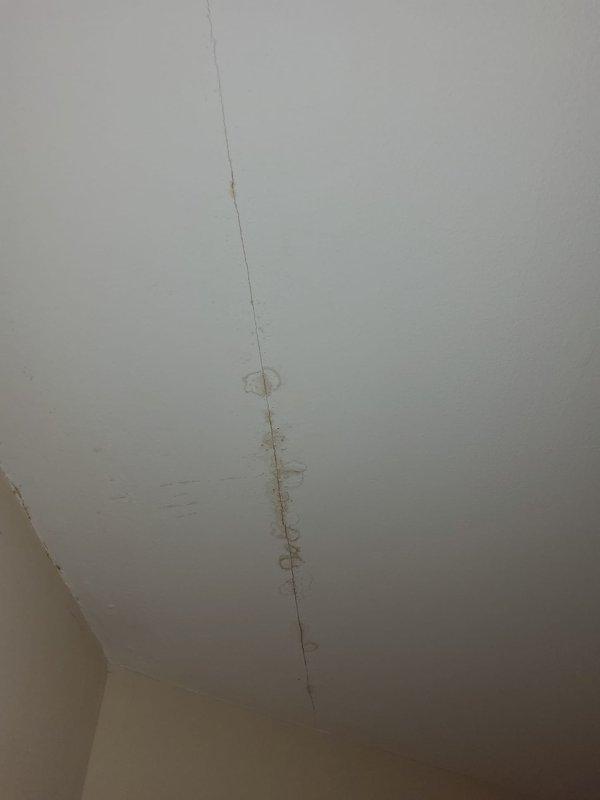 Completed warranty service call to rerun condensate drain line to third-floor console unit. Documented pre-existing ceiling damage including visible cracks and surface deterioration that homeowner attributes to previous drainage issues. No repairs to ceiling damage were performed during this service visit.