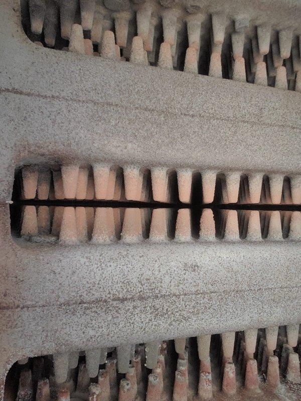 Performed diagnostic service on Weil-McLain hydronic boiler system to address radiator leakage and knocking sounds. Inspection revealed significant corrosion and mineral deposits on the boiler's upper housing and heat exchanger assembly. Documented extensive dust accumulation and wear on the heat exchanger fins, indicating system requires thorough cleaning and possible component replacement to restore proper operation.