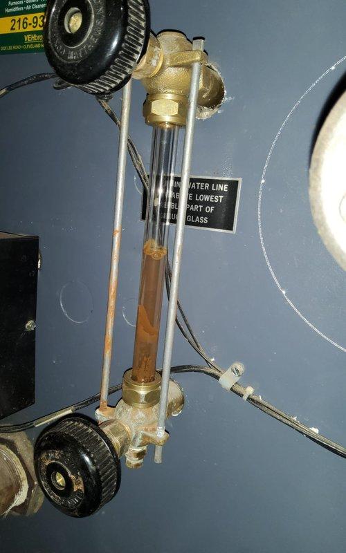 Responded to no-heat service call for 5-year-old thermostat issue. Upon inspection, discovered significant sediment buildup in the boiler system with visible rust accumulation in the sight glass. Found active leak requiring containment with collection bucket; performed system flush and replaced corroded pipe section to restore proper heating function.