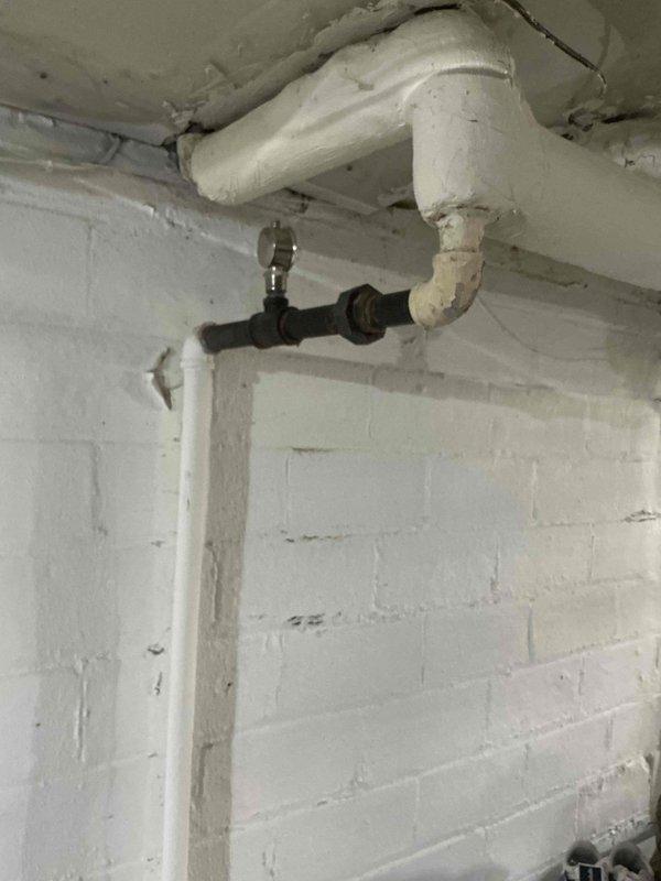 Responded to a service call for a boiler installed in September with a leaking supply line. Identified water leakage at the connection point between PVC and metal fitting, evidenced by water staining on the concrete floor. Placed collection bucket to prevent further water damage while completing necessary repairs to the compromised joint.