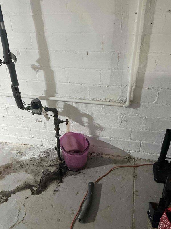 Responded to a service call for a boiler installed in September with a leaking supply line. Identified water leakage at the connection point between PVC and metal fitting, evidenced by water staining on the concrete floor. Placed collection bucket to prevent further water damage while completing necessary repairs to the compromised joint.