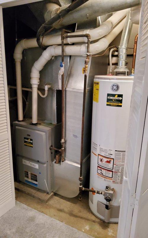 Performed scheduled maintenance tune-up on 5+ year old furnace. Inspected FASCO motor for proper operation and condition, noting no abnormalities. System is installed in utility closet alongside GE water heater with appropriate PVC venting and copper line connections; all components functioning within normal parameters.