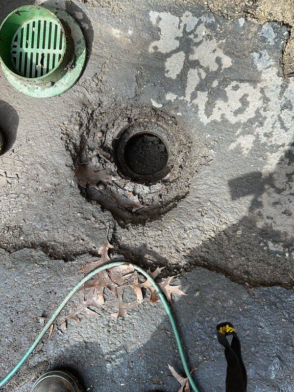 Responded to customer complaint of water backing up near house foundation. Inspection revealed multiple drain openings with significant deterioration, including a circular drain surrounded by cracked concrete with damage radiating outward. Cleared debris from drains and removed accumulated leaves to restore proper drainage functionality and prevent further water accumulation near the structure.