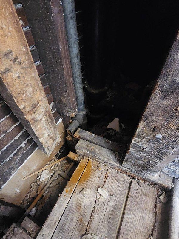 Responded to service call for clogged drain. Conducted thorough inspection using scope camera on exposed shower drain pipe where shower had been previously demolished. Visual inspection of wall cavity revealed possible structural issues affecting drainage system, with photos documenting the condition of aged wooden supports and vertical plumbing infrastructure.