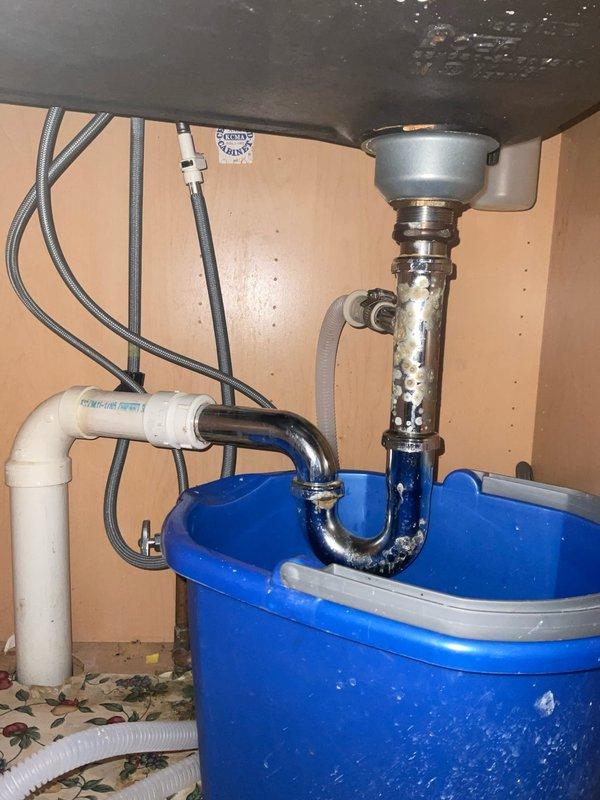 Responded to a service call for a sink leak in a century-old home. Upon inspection, discovered mineral buildup in the drain assembly causing leakage from the metal P-trap. Removed the corroded metal trap, installed new PVC P-trap and drain assembly components, and verified proper drainage with no leaks.
