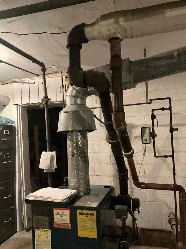 Conducted on-site assessment of a 30+ year old steam boiler that is no longer operational. Visual inspection revealed an aging system with extensive deterioration, requiring complete replacement rather than repair due to the anticipated cost of parts and labor. System evaluation performed between 11:30-1:30, documented with photographs of the existing boiler, ventilation components, and associated plumbing infrastructure in the basement utility area.