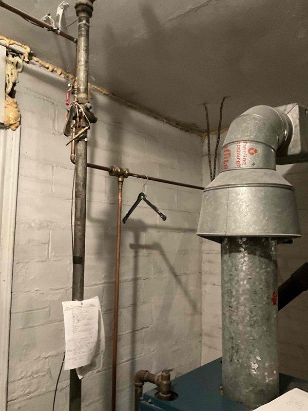 Conducted on-site assessment of a 30+ year old steam boiler that is no longer operational. Visual inspection revealed an aging system with extensive deterioration, requiring complete replacement rather than repair due to the anticipated cost of parts and labor. System evaluation performed between 11:30-1:30, documented with photographs of the existing boiler, ventilation components, and associated plumbing infrastructure in the basement utility area.