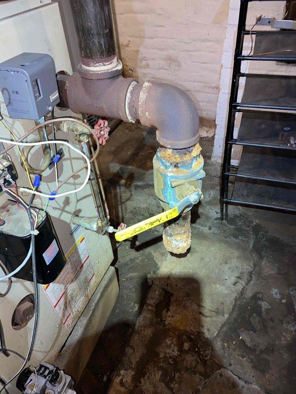 Responded to service call for no heat from aging steam radiator system. Inspection revealed significant corrosion and deterioration at pipe connections, particularly at the main elbow joint where protective insulation has degraded. System restored to operation after clearing blockage and replacing damaged valve components.