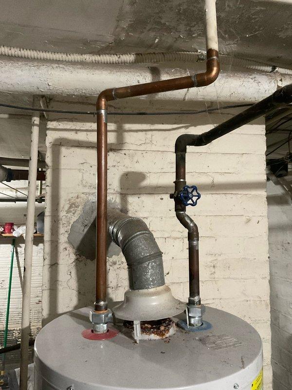 Responded to service call for water heater leaking from bottom with pilot light failure. Upon inspection, determined tank had reached end of life with visible corrosion at vent connection and water damage. Completed installation of new water heater unit, properly connecting copper supply lines, exhaust vent, and expansion tank to existing plumbing infrastructure.