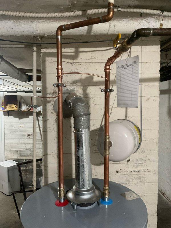 Responded to service call for water heater leaking from bottom with pilot light failure. Upon inspection, determined tank had reached end of life with visible corrosion at vent connection and water damage. Completed installation of new water heater unit, properly connecting copper supply lines, exhaust vent, and expansion tank to existing plumbing infrastructure.