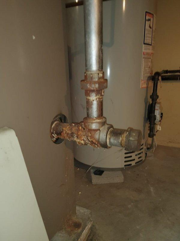 Responded to service call for intermittent heating issue on 30-year-old hot water boiler system. Inspection revealed significant corrosion and rust on pipe fittings at water heater connection points, indicating possible leakage. Examination of internal components showed aging copper pipes with valve deterioration and mineral buildup on heat exchanger elements, consistent with the system's advanced age.