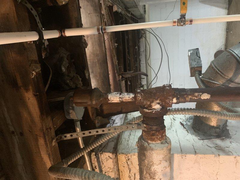 Inspected 13-year-old steam boiler system to provide estimate for pipe replacement. Documented extensive corrosion and mineral deposits on existing copper piping, particularly at valve junctions, with visible water damage to surrounding areas. Noted previous partial replacement with PVC piping, but recommended complete replacement of remaining deteriorated copper sections to prevent potential failure.