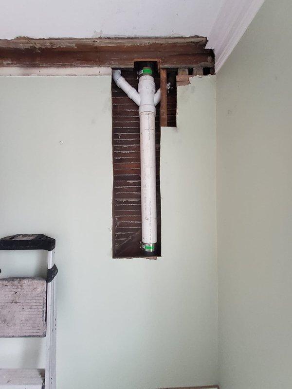 Accessed interior wall by creating opening to expose existing shower drain wye fitting. Removed old wye and installed new PVC wye with 2" drain for shower, including cap for bath authority's future shower stall installation. Completed all necessary plumbing connections through existing wooden framework while working around multiple existing pipe systems.