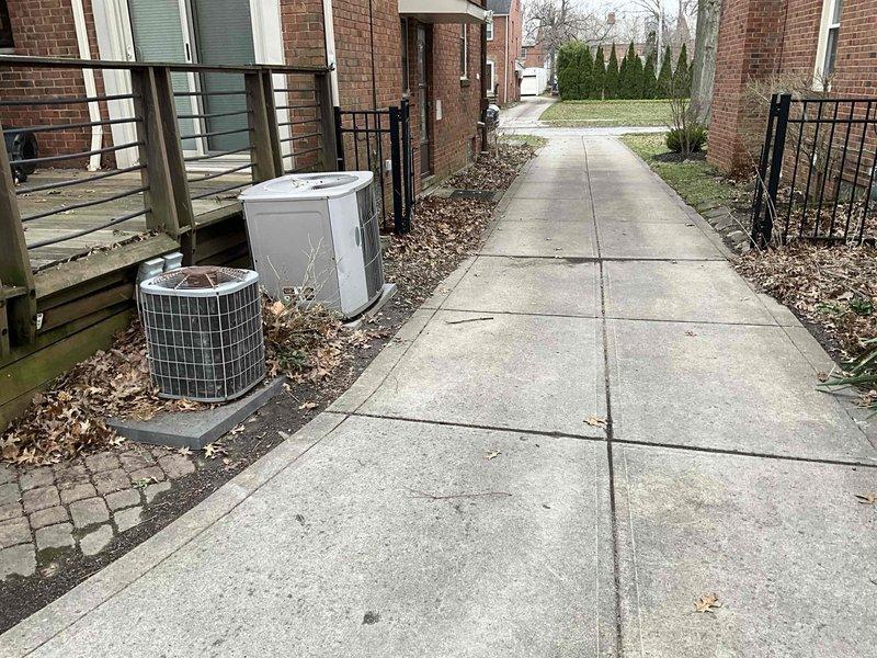 Conducted site assessment for replacement of two existing AC units with heat pump systems to create a hybrid heating solution. Exterior inspection revealed two condenser units (cylindrical and box-shaped) positioned alongside concrete walkway near residential building. Interior evaluation of mechanical room showed existing furnace system with connected ductwork, air handler, and associated PVC drainage pipes that will be integrated with new heat pump installation for optimal hybrid operation.