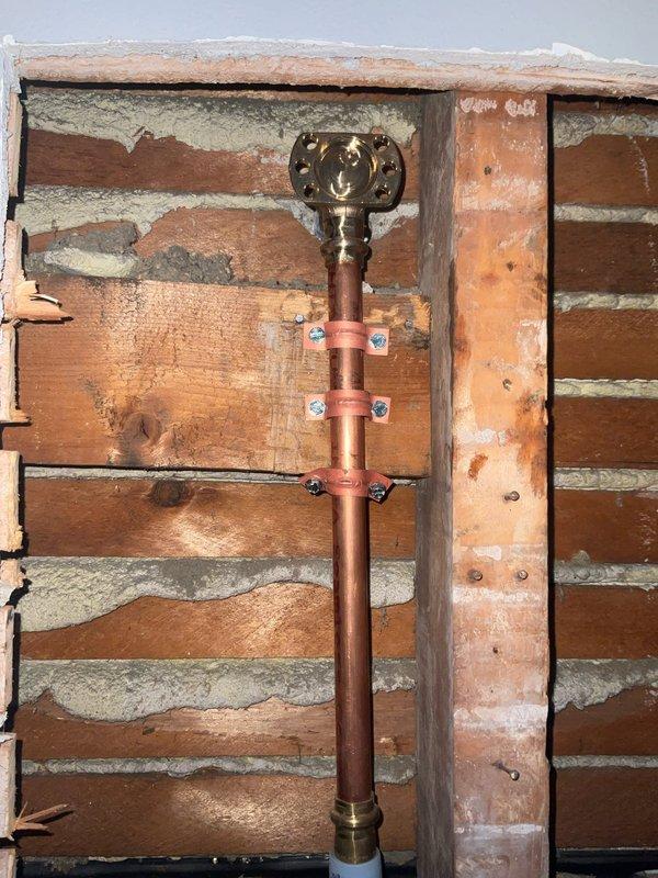 Responded to callback regarding recent hot/cold water nozzle installation. Diagnosed issue where hot water was not flowing when both valves were open, requiring customer to shut off cold water for hot water function. Also addressed newly reported wobble in shower arm connection to wall. Inspection of wall cavity revealed proper copper pipe installation with brass fittings and appropriate securing brackets, requiring adjustment to valve cartridge to resolve water flow issue and tightening of shower arm connection to eliminate movement.