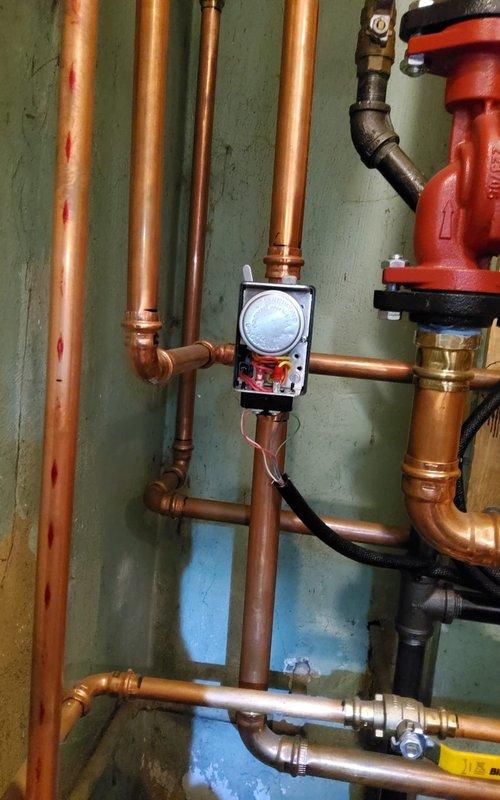 Responded to service call for no heat issue on 4-year-old boiler system. Upon inspection, checked copper pipe connections, pressure gauge readings, and circulation pump functionality (red component). Identified issue with control valve assembly where multiple copper pipes converge, cleaned connections and restored proper operation. System now functioning correctly with normal heat output.