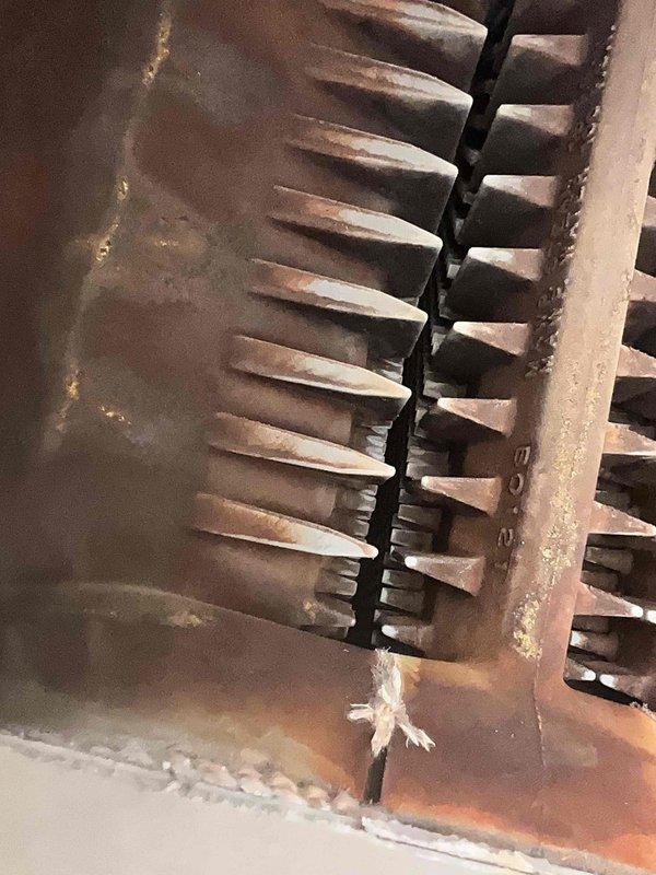 Performed boiler tune-up service, inspecting burner flames which showed proper combustion with characteristic purple-pink coloration. Observed significant oxidation and rust buildup on heat exchanger fins, but system remains operational. Documentation photos taken of burner assembly and heat exchanger condition for service records.