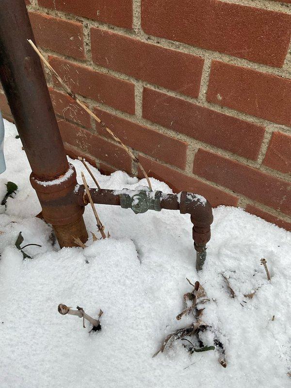 Inspected and capped an unused gas line at 60-year-old residence. Verified proper sealing of valve connection on exterior copper pipe installation to prevent leakage. Snow accumulation around pipe base was cleared to ensure complete visual inspection of all fittings.