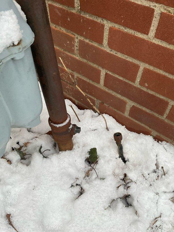 Inspected and capped an unused gas line at 60-year-old residence. Verified proper sealing of valve connection on exterior copper pipe installation to prevent leakage. Snow accumulation around pipe base was cleared to ensure complete visual inspection of all fittings.
