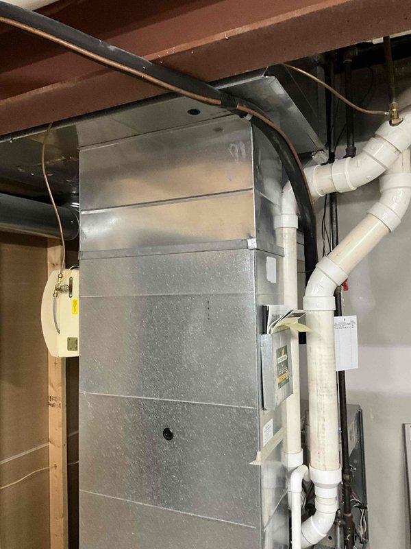 Provided estimate for replacement of 19-year-old non-functional furnace. Examined existing HVAC system in basement/utility room, which includes metallic air handler with PVC drainage pipes, control panel, and proper electrical connections mounted against wall under wooden joists.