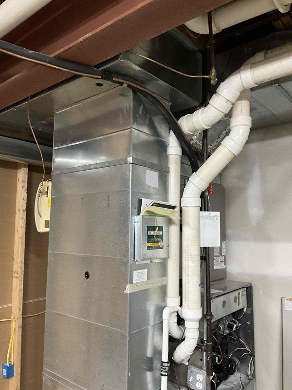 Provided estimate for replacement of 19-year-old non-functional furnace. Examined existing HVAC system in basement/utility room, which includes metallic air handler with PVC drainage pipes, control panel, and proper electrical connections mounted against wall under wooden joists.