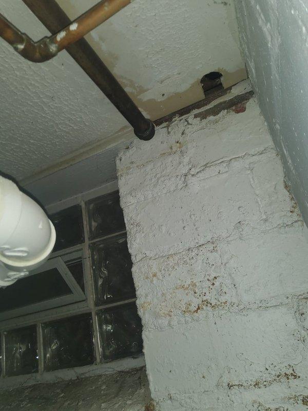 Removed deteriorated radiator unit and capped water lines below floor level in utility area. Observed significant water damage on surrounding walls and ceiling, with evidence of moisture issues affecting the brick/concrete surfaces. Completed line isolation to prevent leakage from disconnected system.