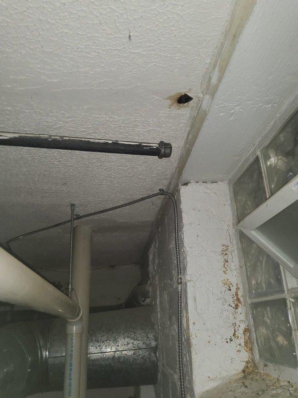 Removed deteriorated radiator unit and capped water lines below floor level in utility area. Observed significant water damage on surrounding walls and ceiling, with evidence of moisture issues affecting the brick/concrete surfaces. Completed line isolation to prevent leakage from disconnected system.