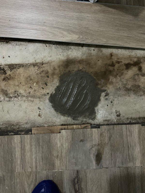 Removed existing drain and water lines from bar area, capped water lines beyond the valves, and cut drain to floor level. Applied hydraulic cement to seal the floor opening where drain was removed. Documented the repair with photos showing the cemented floor patch and surrounding wall area with exposed wooden sections where plumbing fixtures were previously installed. Customer will handle bar removal separately.