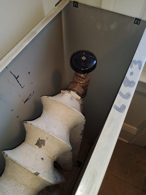 Replaced deteriorated plumbing traps in mechanical enclosure, addressing significant corrosion and paint deterioration on radiator system and associated valve components. Service included replacement of aging brass valve fittings and repair of connection points showing signs of water damage and wear.