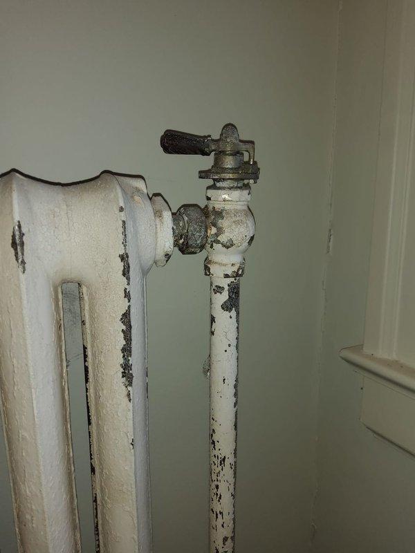 Replaced deteriorated plumbing traps in mechanical enclosure, addressing significant corrosion and paint deterioration on radiator system and associated valve components. Service included replacement of aging brass valve fittings and repair of connection points showing signs of water damage and wear.