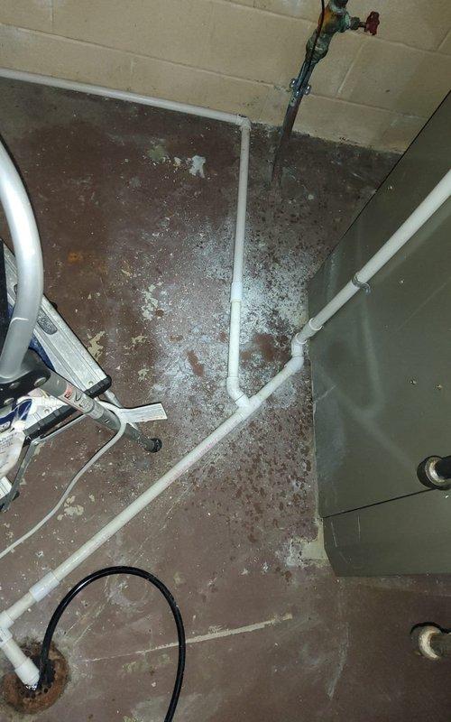 Performed routine A/C maintenance on MVP unit of undetermined age. Inspected drainage system with visible PVC configuration and water valve functionality. Weather conditions during service were mild with intermittent showers, which was noted for system performance evaluation.