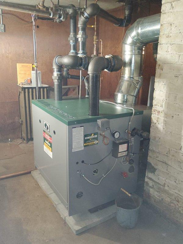 # HVAC Install - Steam Gas Boiler

Completed full steam boiler replacement in vacant residential property under financing arrangement. Coordinated asbestos abatement prior to installation to ensure safe working conditions and regulatory compliance.

Removed existing boiler system and installed new steam gas boiler unit on concrete pad in basement mechanical room. Connected system to existing steam distribution piping using black iron pipe with appropriate fittings and isolation valves. Installed new backflow preventer to protect potable water supply and new automatic water feeder to maintain proper boiler water levels. Configured venting system with metallic ductwork to ensure proper combustion air supply and exhaust ventilation per manufacturer specifications and local codes.

Installed new thermostat and wired to boiler controls for proper system operation. Tested all safety controls including pressure relief valve, low water cutoff, and gas valve operation. Pressurized system, check