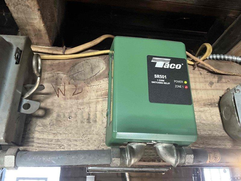 Responded to service call for boiler estimate. Upon arrival, assessed existing heating system including Taco SR501 switching relay zone control and aging boiler unit in basement mechanical room. Documented current system configuration with copper piping connections, zone control wiring, and pressure relief valve assembly for estimate preparation.