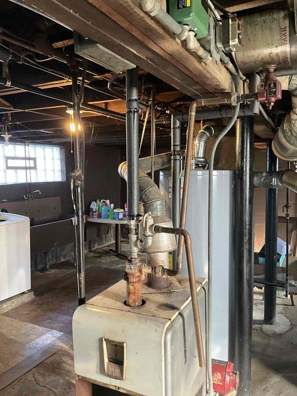 Responded to service call for boiler estimate. Upon arrival, assessed existing heating system including Taco SR501 switching relay zone control and aging boiler unit in basement mechanical room. Documented current system configuration with copper piping connections, zone control wiring, and pressure relief valve assembly for estimate preparation.