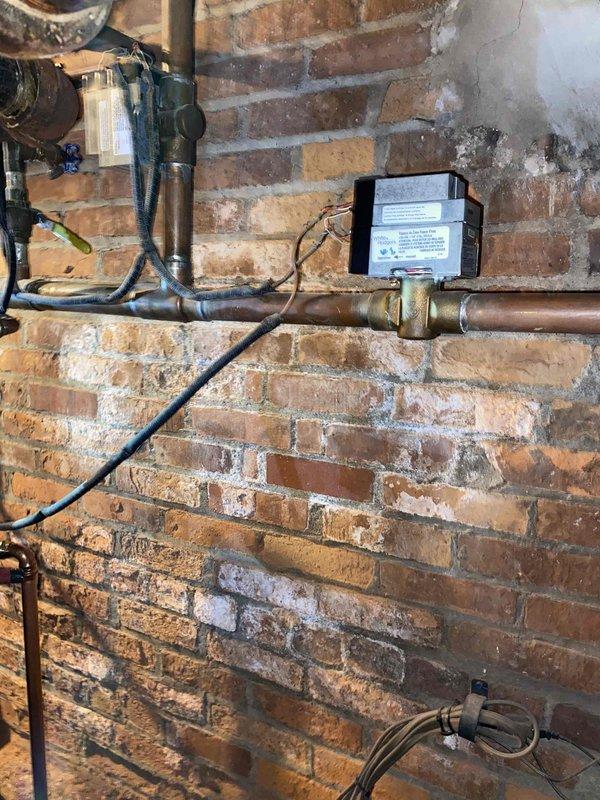 Responded to service call for dripping boiler on one-year-old unit. Upon inspection of the mechanical room, identified minor leak at copper piping connection point near control module. Tightened fitting, verified all valve connections, and confirmed proper operation of boiler system with no further water discharge observed.