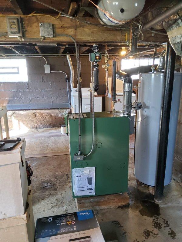 Completed installation of new hot water boiler system for second floor apartment heating. Removed and replaced existing boiler with new green unit mounted on concrete pad in basement mechanical room. Installed new thermostat, expansion tank, backflow preventer/PRV combination valve, vertical air eliminator, and circulating pump. Removed obsolete ceiling-mounted expansion tank from overhead joists. Connected all components using existing 3/4 inch copper supply lines with new brass fittings and valves. Verified proper operation of all controls, tested system pressure, purged air from lines, and confirmed adequate heat delivery to second floor zone. All equipment secured and operational per manufacturer specifications.