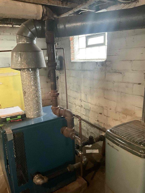 Conducted on-site estimate for steam boiler system replacement in residential basement. Evaluated existing teal-colored boiler unit with associated ductwork, piping infrastructure, and distribution system. Documented current equipment condition, photographed mechanical room layout including concrete block construction, and assessed installation requirements for new system.
