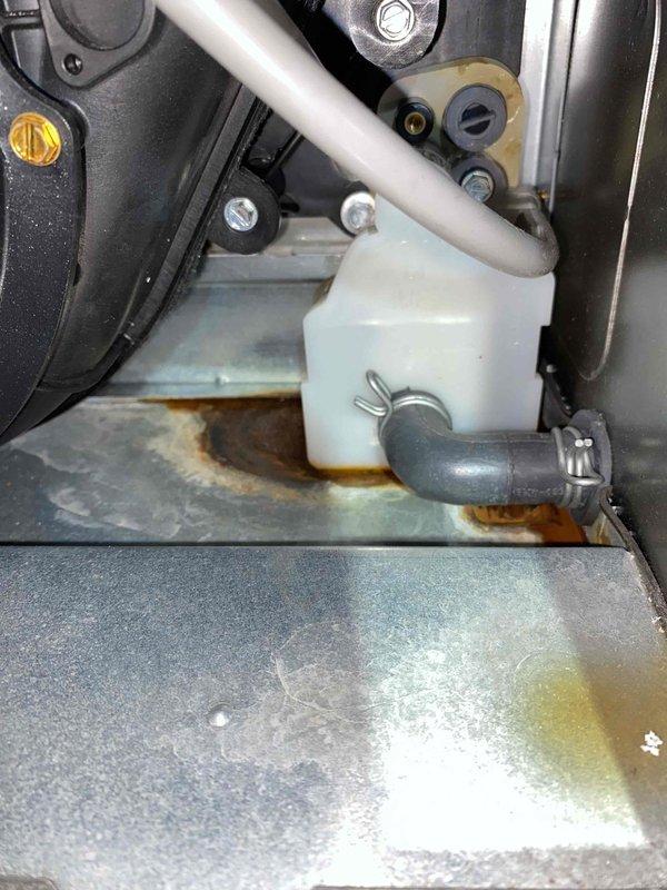 Responded to water leak complaint on two-year-old furnace with visible rust concerns. Upon inspection, identified condensate drainage issue causing water accumulation at base of unit. Observed significant rust staining on metal base panel beneath condensate collection system and around drain components. Inspected condensate trap, drain lines, and associated plumbing connections for blockages or improper installation. Photographed affected areas showing rust damage on base panel and condensate system components. Addressed drainage concern to prevent further water leakage and corrosion damage to furnace cabinet.