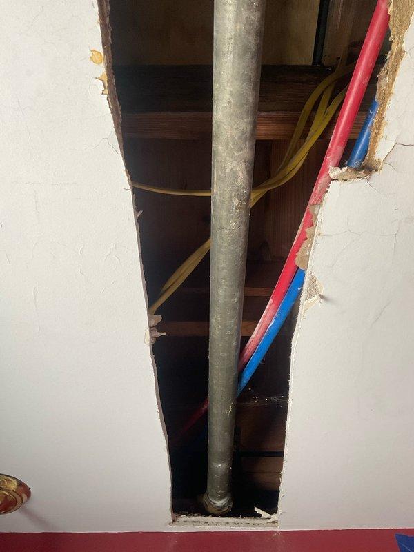 Completed comprehensive plumbing stack assessment and repair work involving sump pump system and exterior spigot connections over a four-day period with two-person crew. Performed exploratory demolition of interior wall and ceiling sections to access concealed plumbing infrastructure, exposing vertical stack assembly, supply lines, and drainage components. Documented extensive water damage and deterioration to wall framing and drywall materials, indicating previous moisture intrusion requiring remediation prior to system repairs and wall restoration.