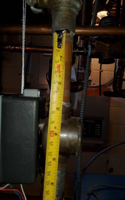 Responded to service call for water accumulation at base of heating unit. Upon arrival, conducted thorough inspection of boiler system and associated piping. Identified corroded copper piping with visible oxidation and deterioration on vertical pipe assembly. Documented measurements of affected piping sections and photographed corroded areas showing significant patina buildup and multiple coupling bands with surface corrosion. Assessed electrical components and control panel connections in proximity to water source. Determined age of equipment could not be verified from available documentation or unit labeling, complicating assessment of expected service life and replacement considerations.
