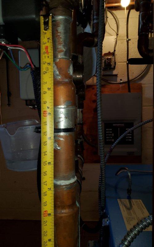Responded to service call for water accumulation at base of heating unit. Upon arrival, conducted thorough inspection of boiler system and associated piping. Identified corroded copper piping with visible oxidation and deterioration on vertical pipe assembly. Documented measurements of affected piping sections and photographed corroded areas showing significant patina buildup and multiple coupling bands with surface corrosion. Assessed electrical components and control panel connections in proximity to water source. Determined age of equipment could not be verified from available documentation or unit labeling, complicating assessment of expected service life and replacement considerations.
